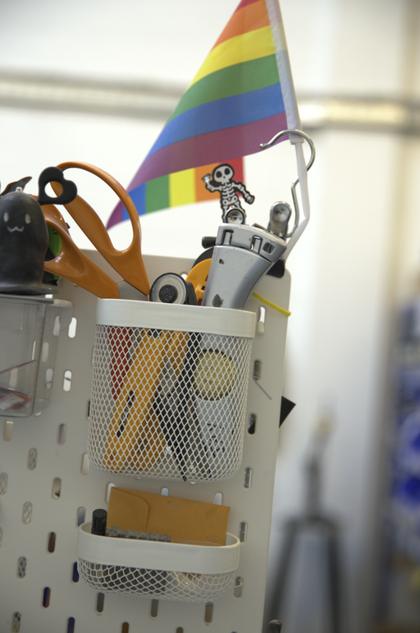 A pegboard of workshop tools with a rainbow flag