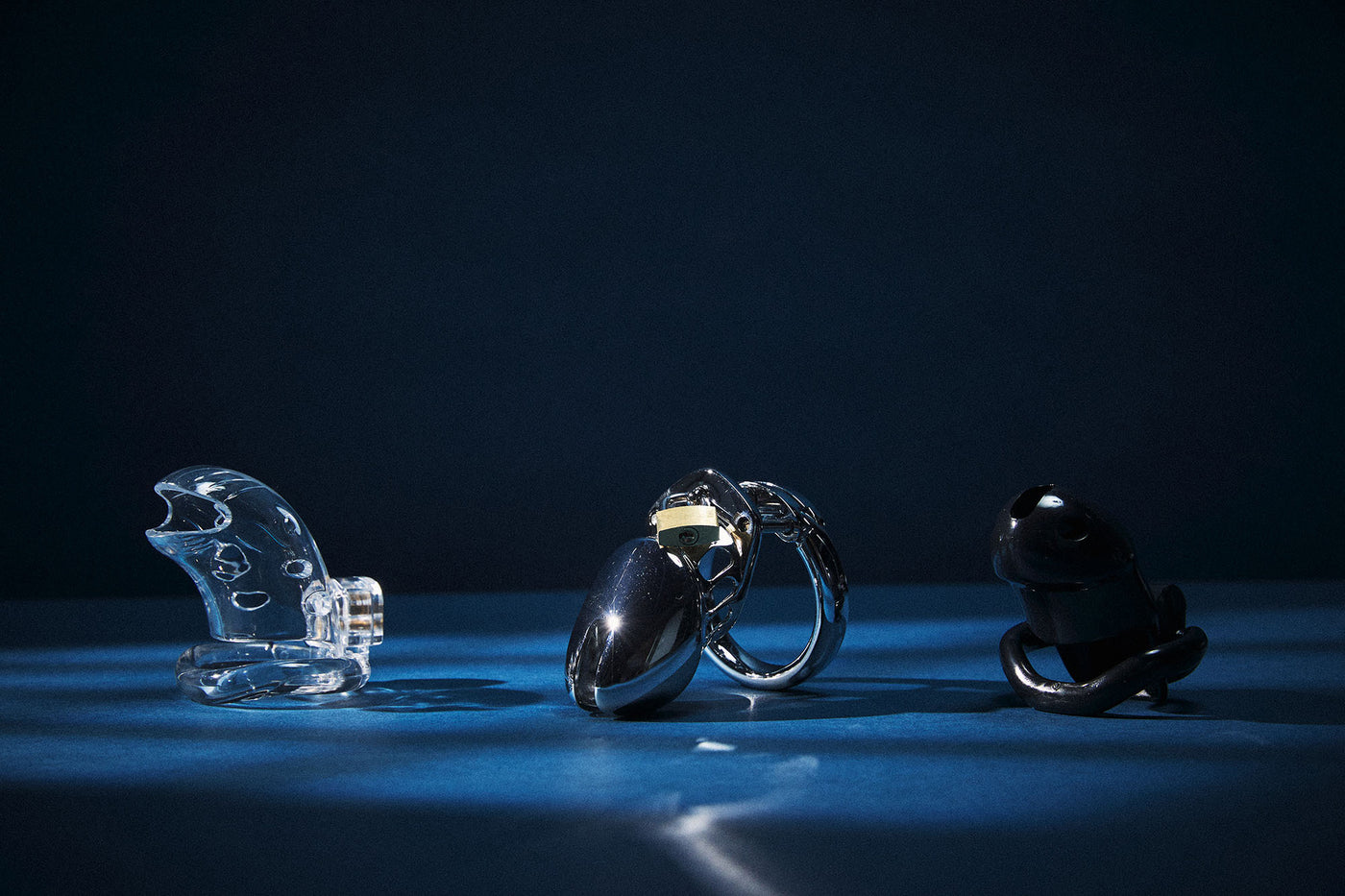 Three metallic objects on a reflective surface with a dark background