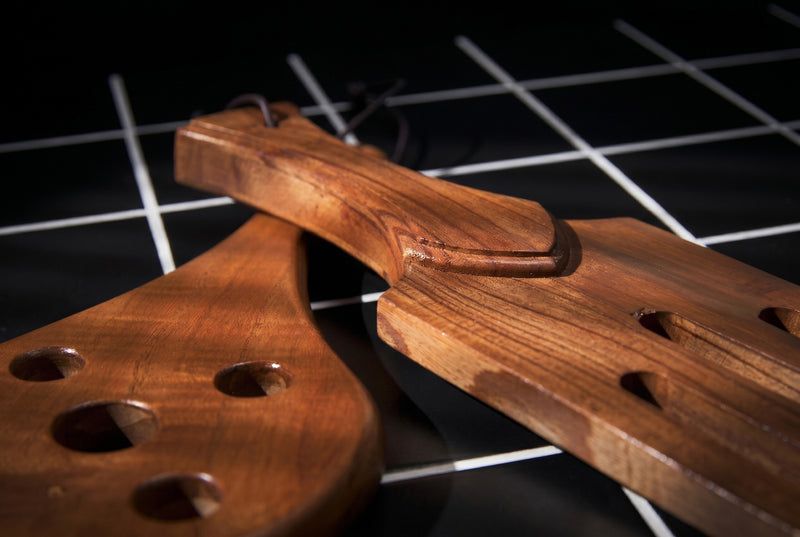 Wooden paddles on a dark surface with grid pattern