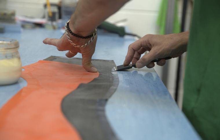 Hands cutting sheet latex with a blade